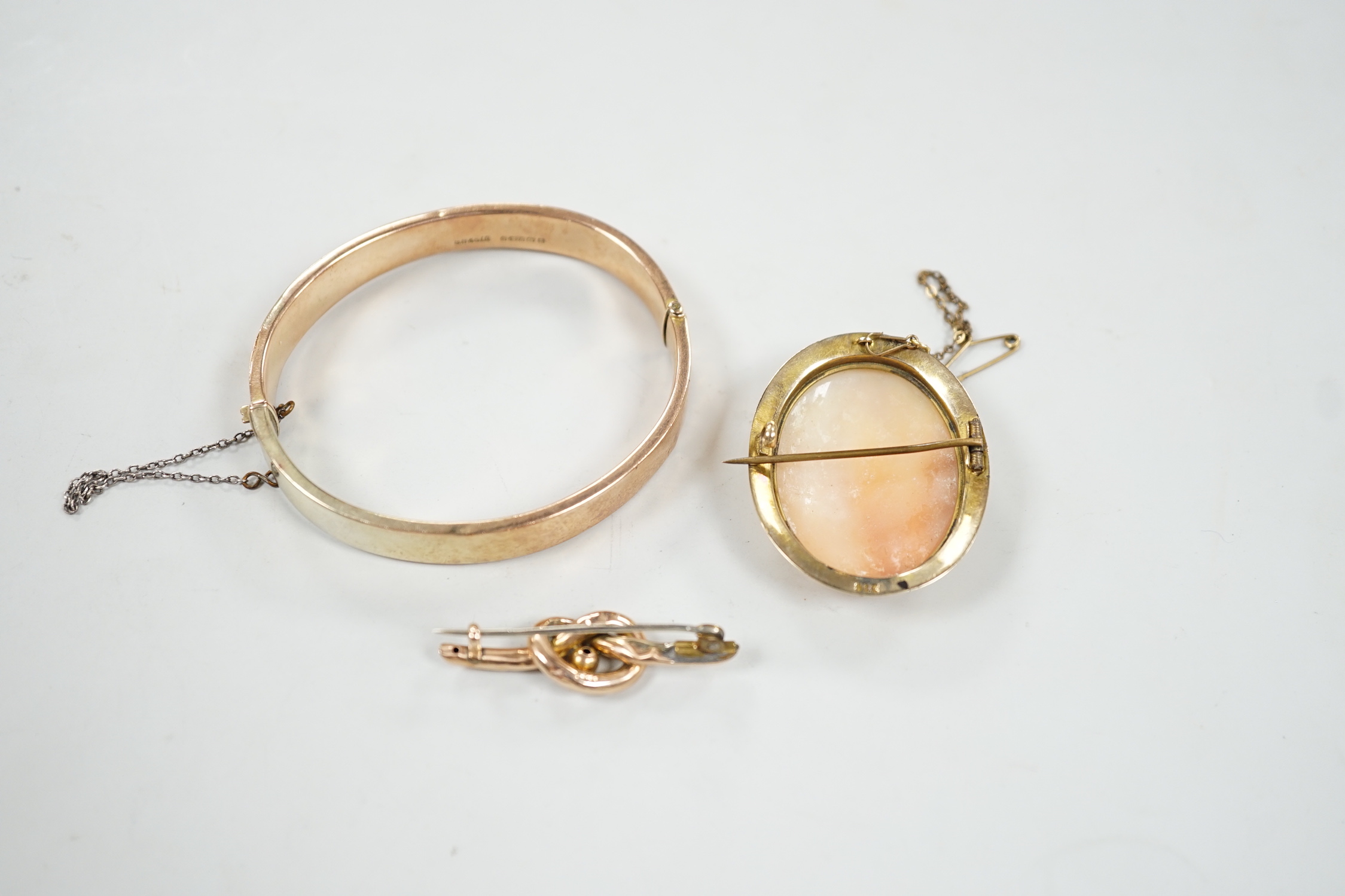 A 9ct mounted oval cameo shell brooch, 41mm, a 9ct gold bangle and a 9ct knot brooch